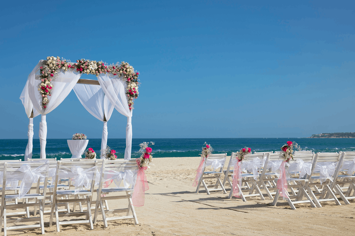 Ceremonia de boda frente al mar en Krystal Grand Los Cabos con altar floral, sillas blancas y vista al Mar de Cortés.